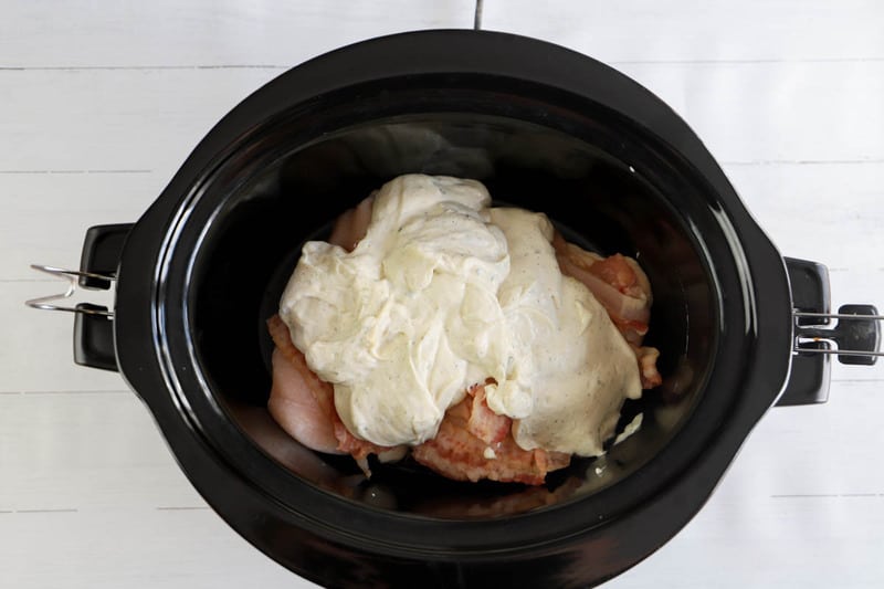 pouring sauce over chicken in the slow cooker