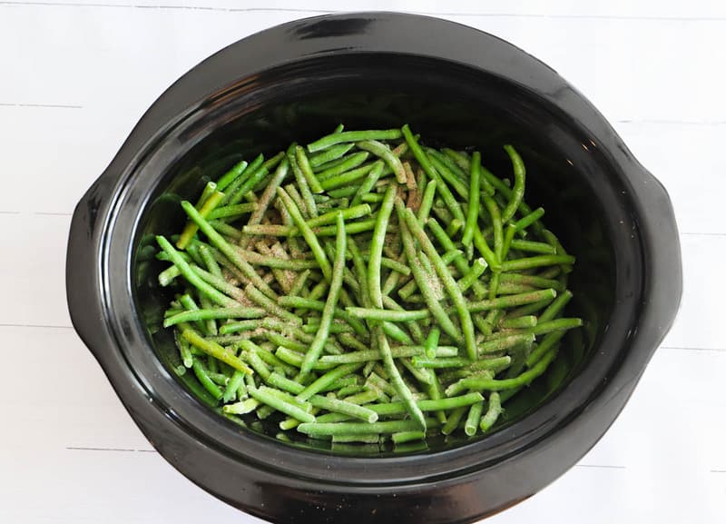 adding seasoning to the green beans