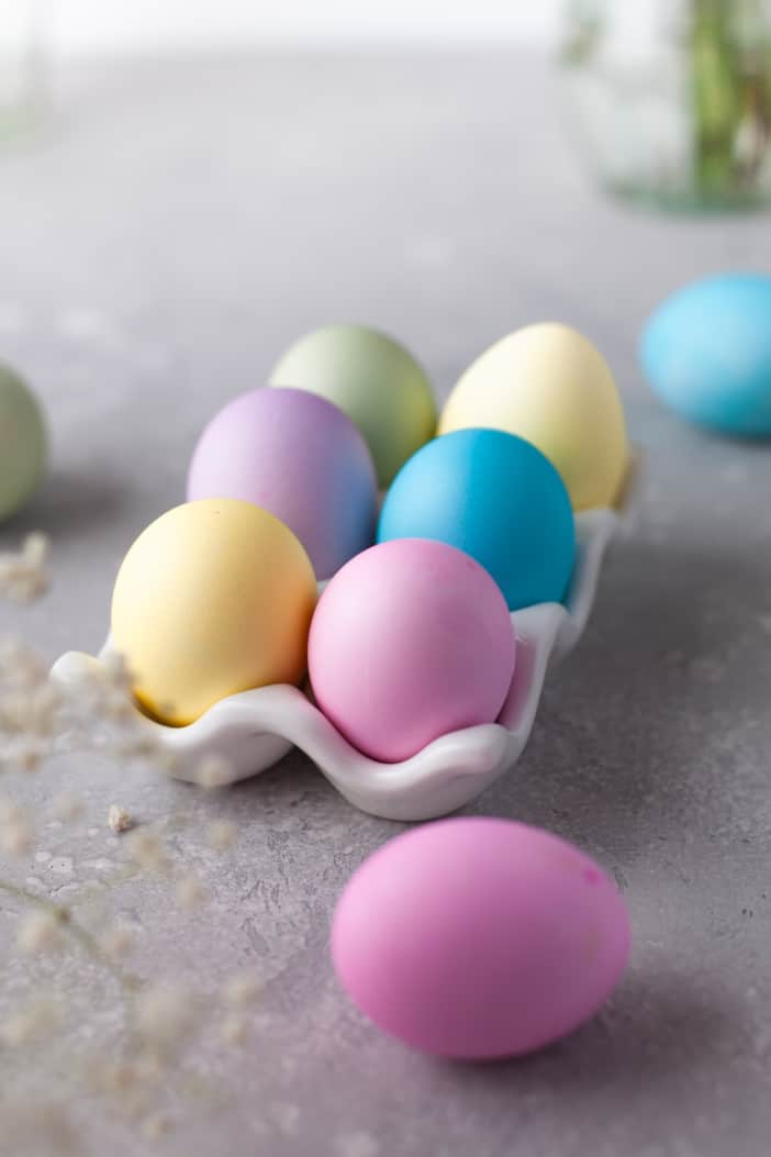 Dyed eggs in an egg carton for holding.