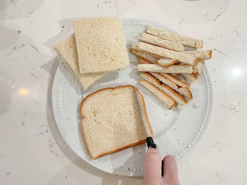 French Toast bread with crust cut off on white plate.