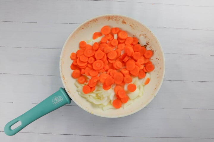 adding carrots and onions to a skillet