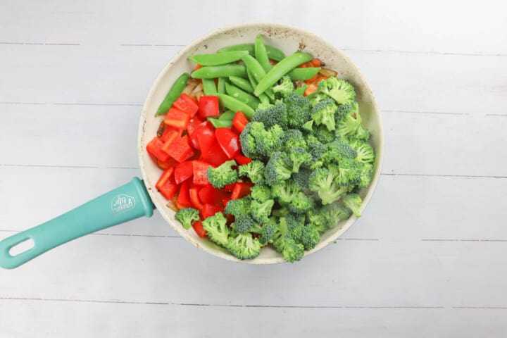 adding more veggies to a skillet