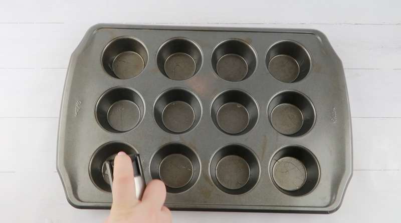 spraying muffin tin with oil