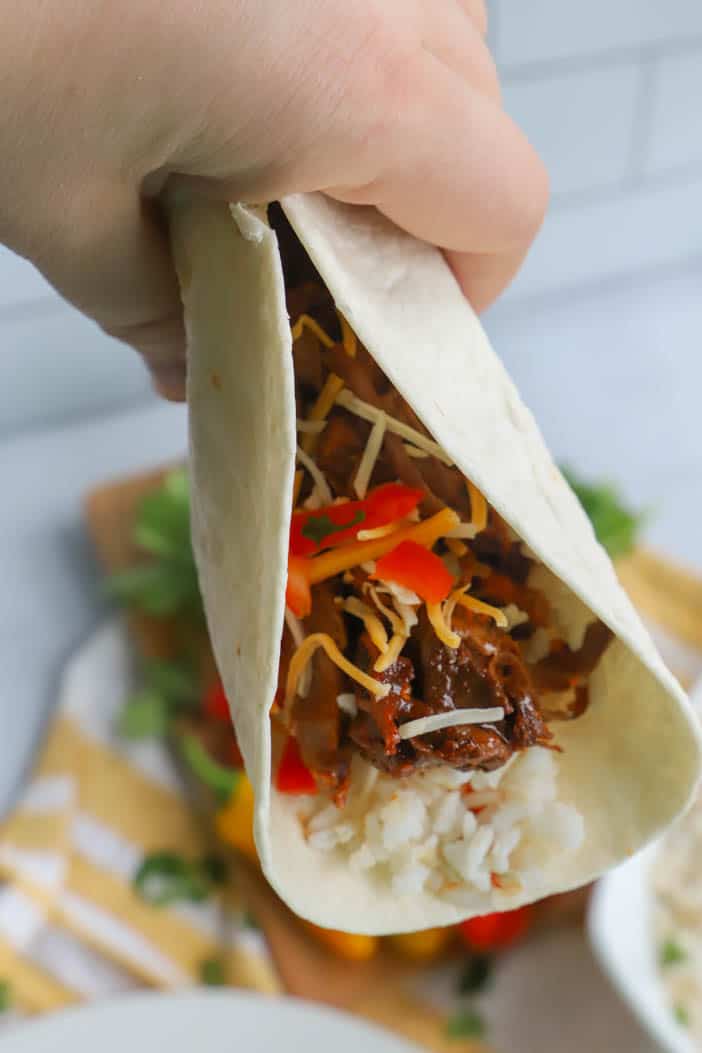 Slow Cooker Shredded Beef Tacos wrapped in a tortilla