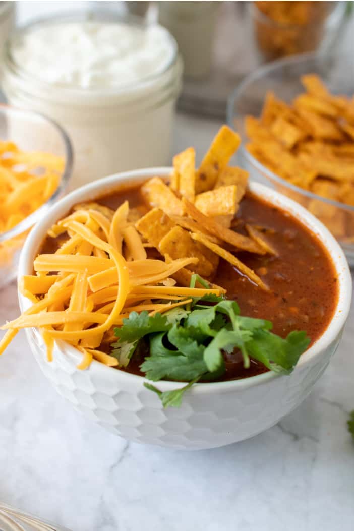 Taco Soup with shredded cheese and chips.