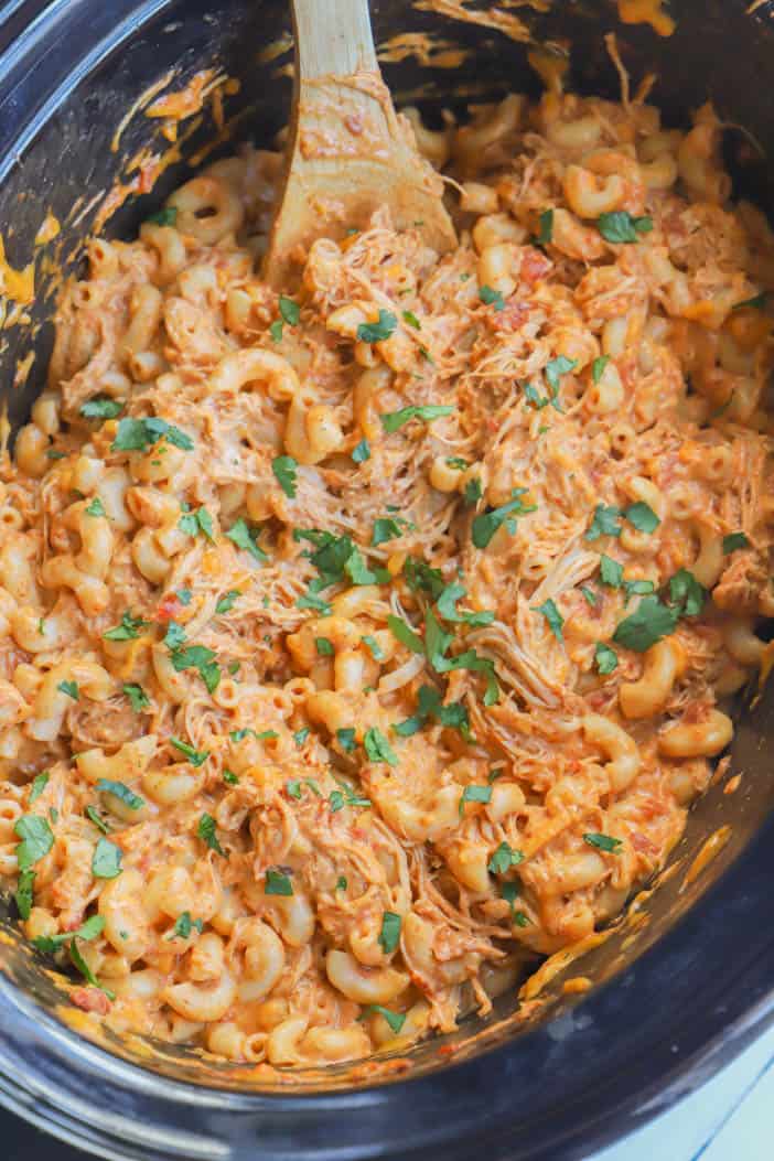 cooked Slow Cooker Enchilada Pasta in the slow cooker with a wooden spoon