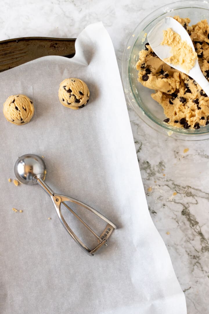scooping chocolate chip cookies on a pan