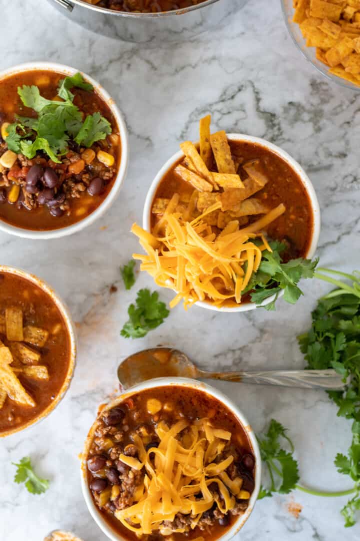 turkey taco soup in small white bowls with different toppings