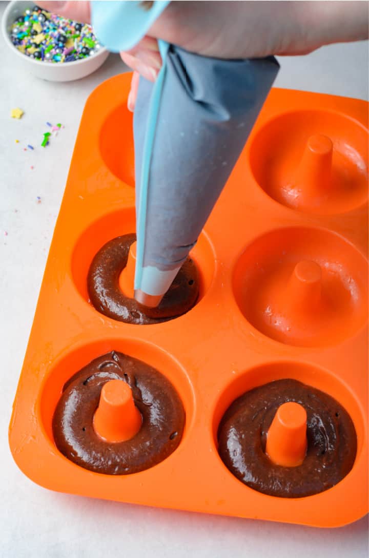 piping the doughnut batter into the doughnut baking tray