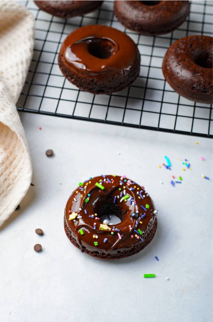 topping the glazed doughnut with multicolored sprinkles