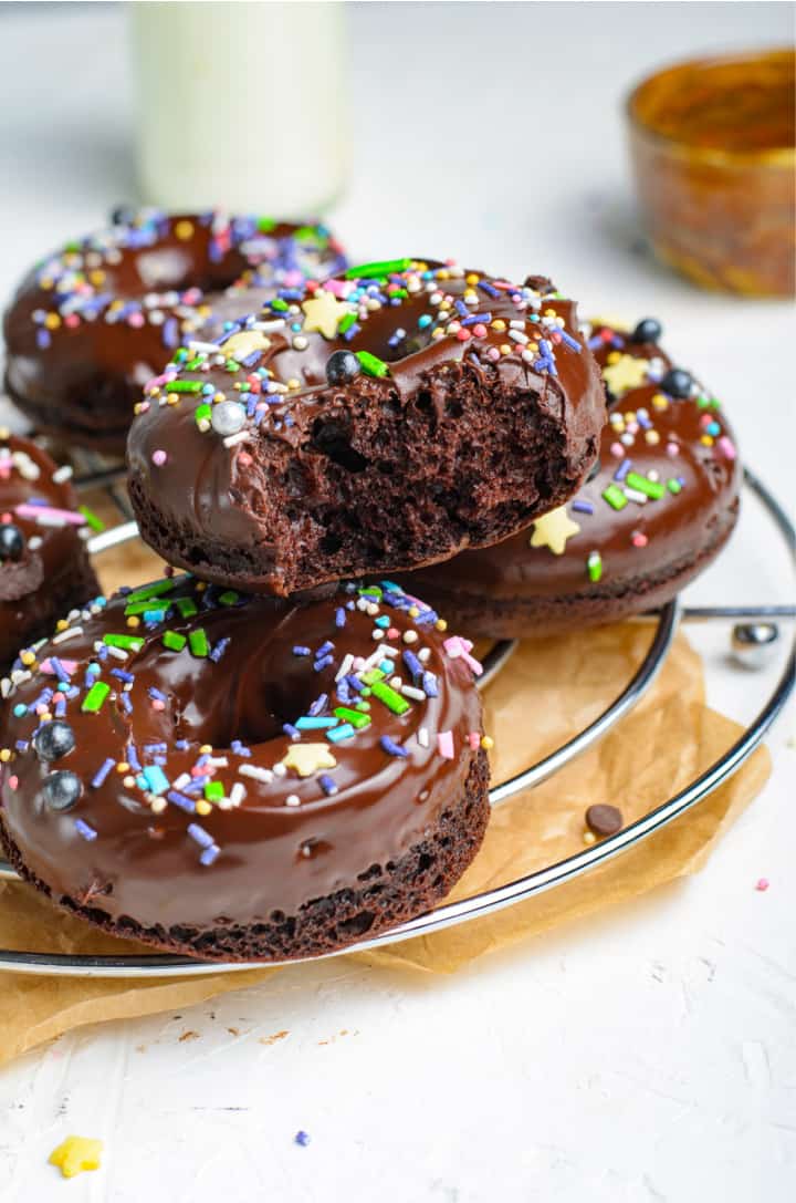 closeup of doughnuts on wire rack with a bit taken out of one doughnut