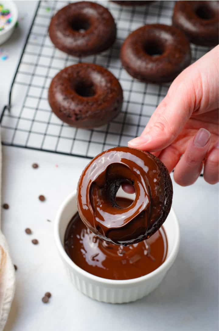 dipping a doughnut into the chocolate glaze