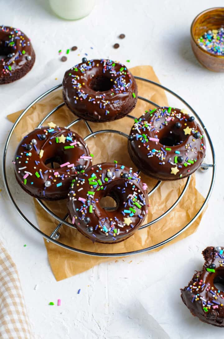 Baked Chocolate Doughnuts on wire rack topped with glaze and sprinkles