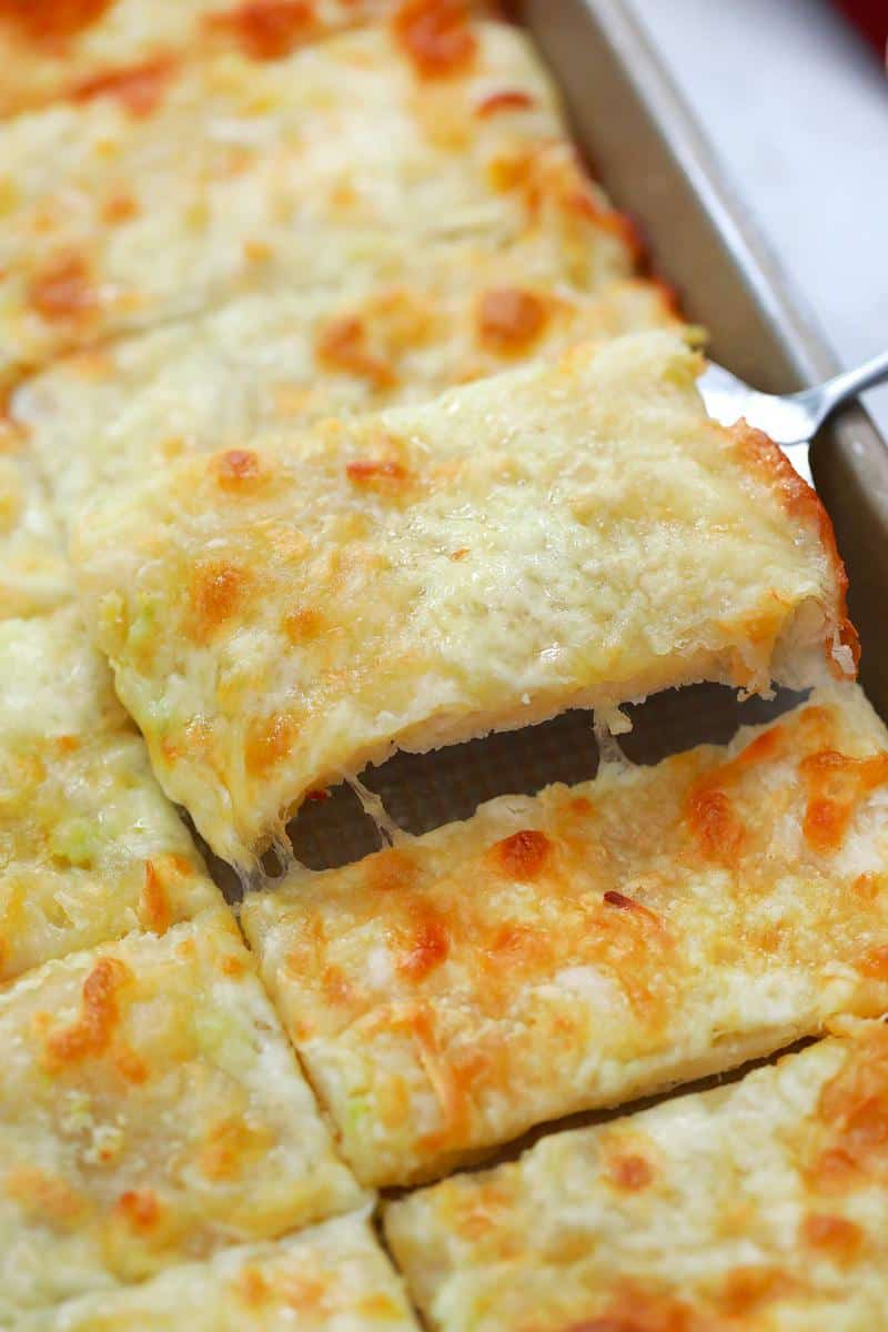 Garlic Breadsticks on baking pan being served with spatula