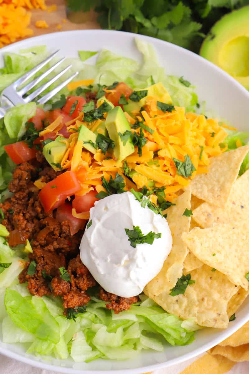 closeup of taco salad in white bowl with all the toppings