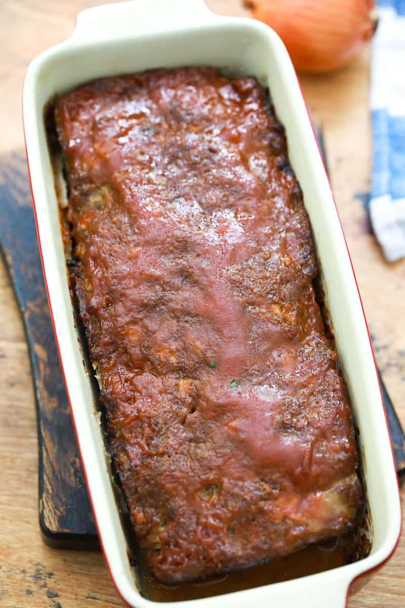 cooked meatloaf in pan on wooden serving board