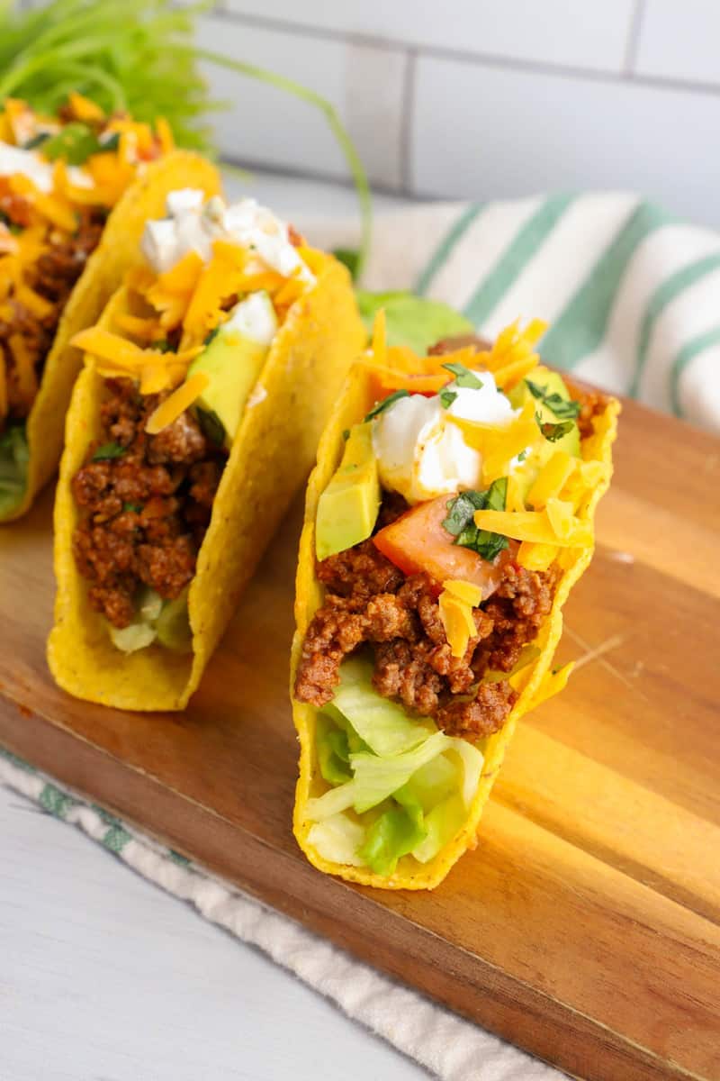 close up shot of completed tacos on wooden serving board