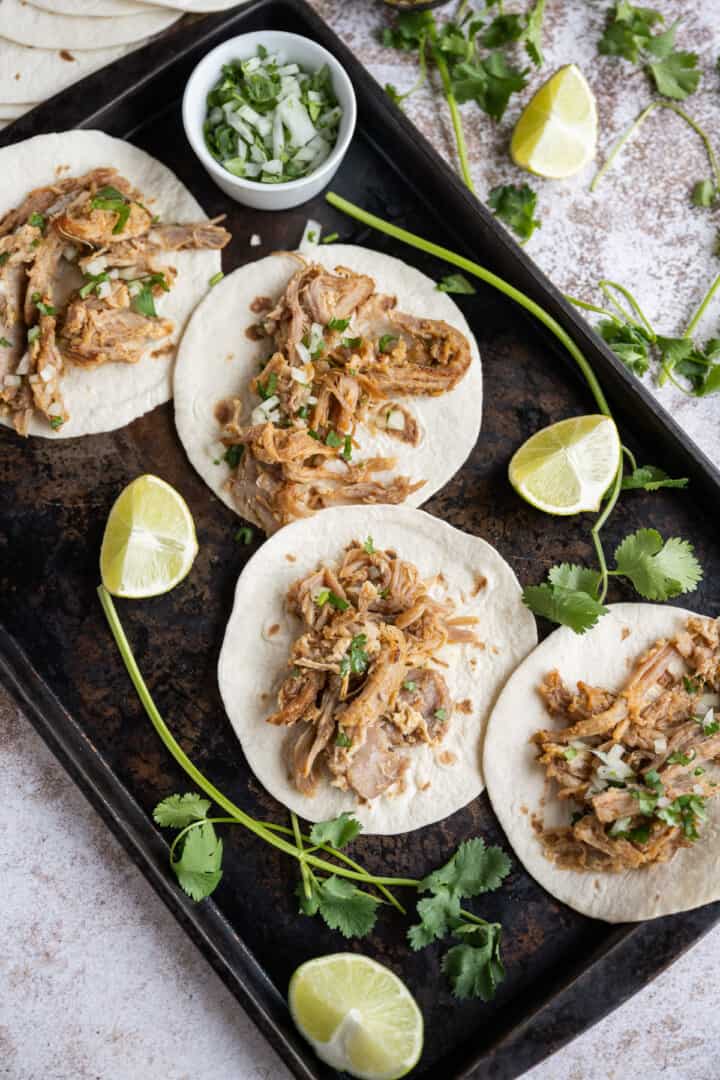 Slow Cooker Carnitas on tray complete on soft tortillas