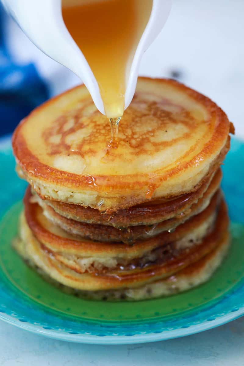 pouring syrup over pancakes
