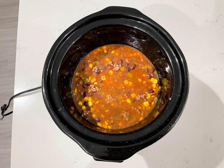 adding remaining soup ingredients to the slow cooker.