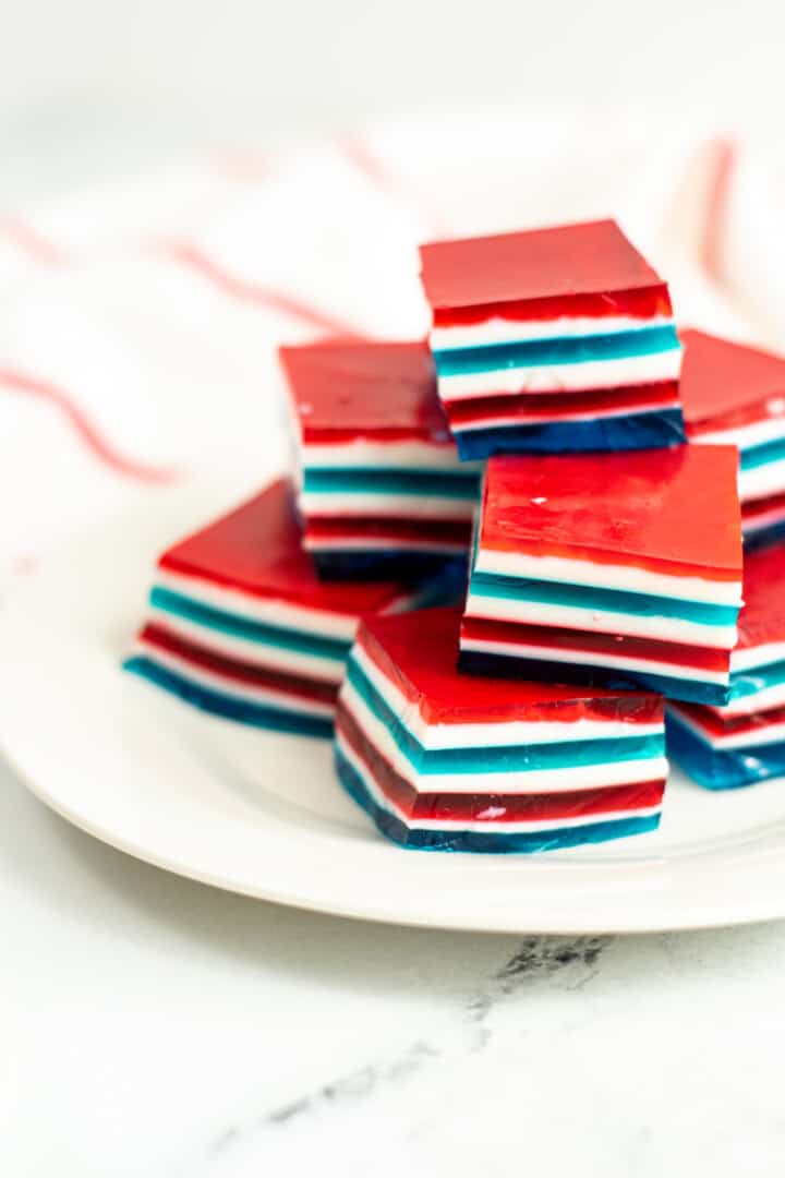 patriotic red white and blue Jello sliced in cubes and stacked on a white plate