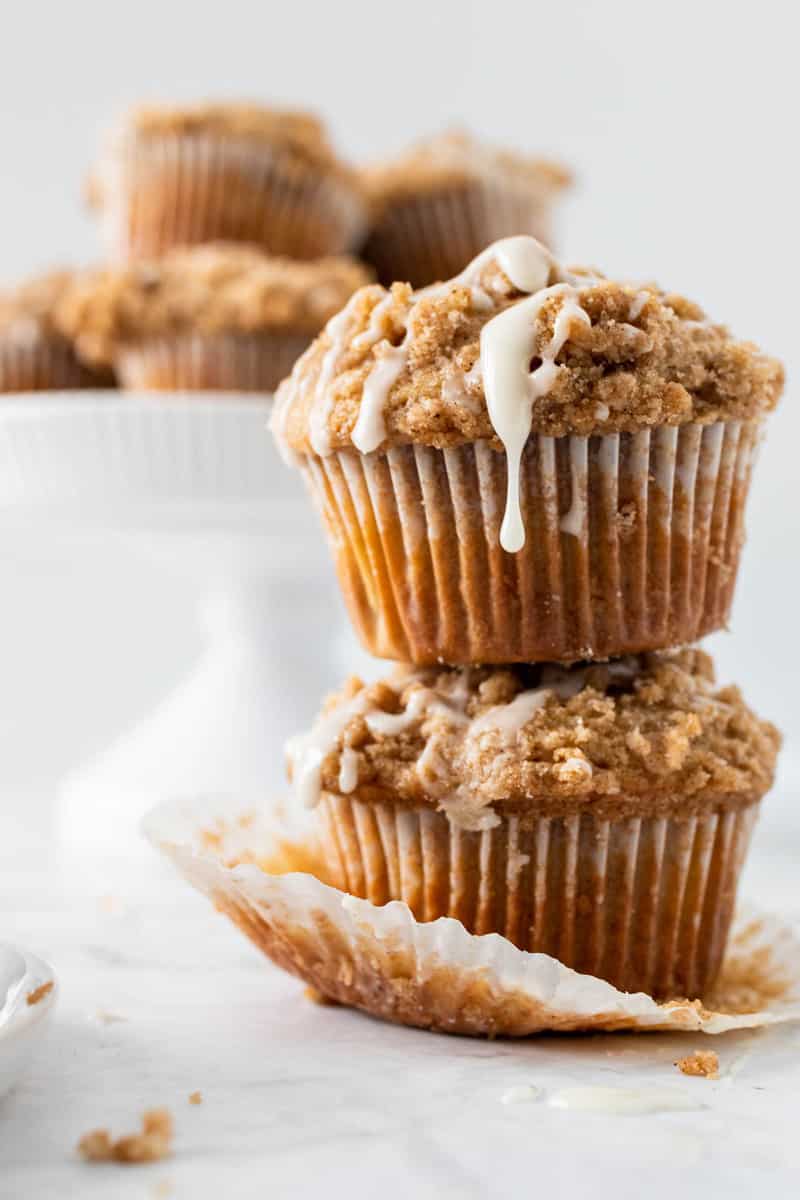 close up shot of two stacked coffee cake muffins with glaze dripping down the side