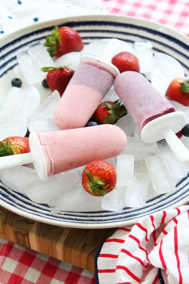 yogurt popsicles on a plate of ice with strawberries.
