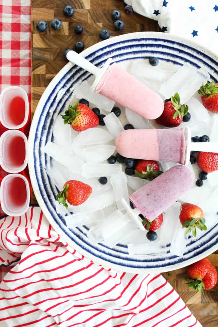 Yogurt Popsicles on a blue and white plate with ice for serving.