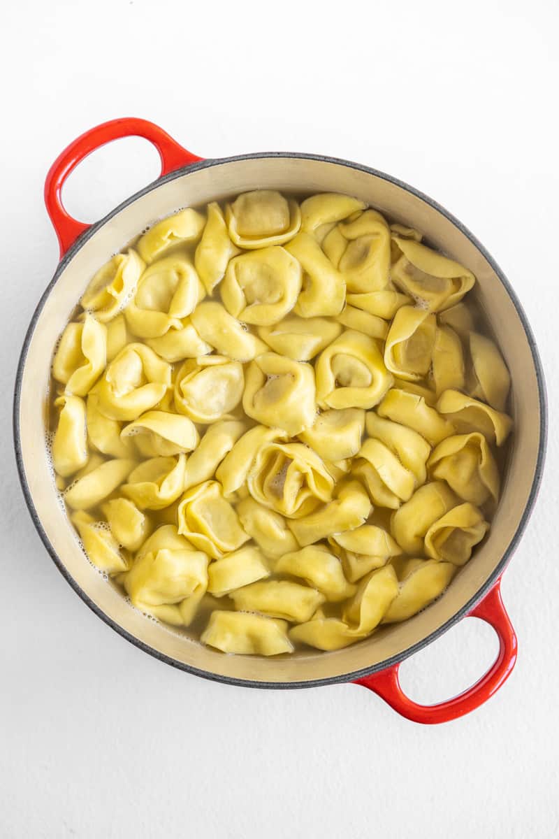 tortellini in a red and white pot about to boil