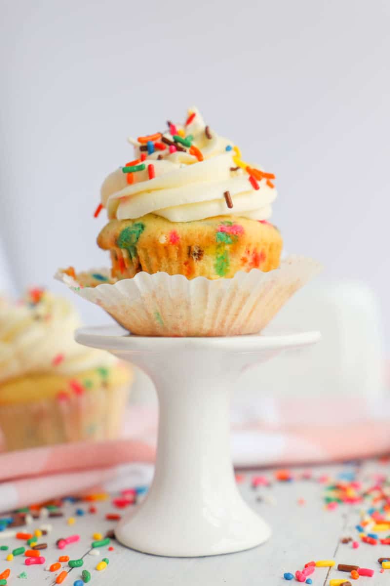 Funfetti cupcake with wrapper coming off on stand