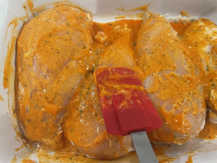 spreading buffalo sauce on the chicken