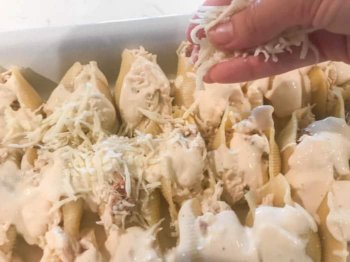 topping the chicken alfredo shells with cheese.