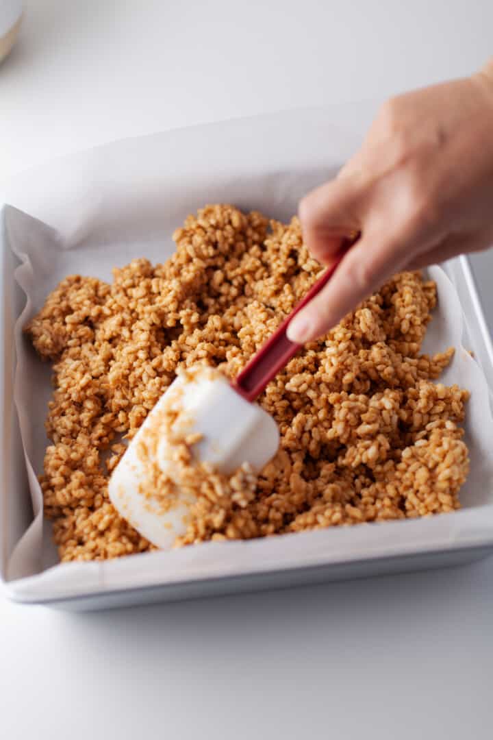 spreading peanut butter rice krispies mix into a baking pan