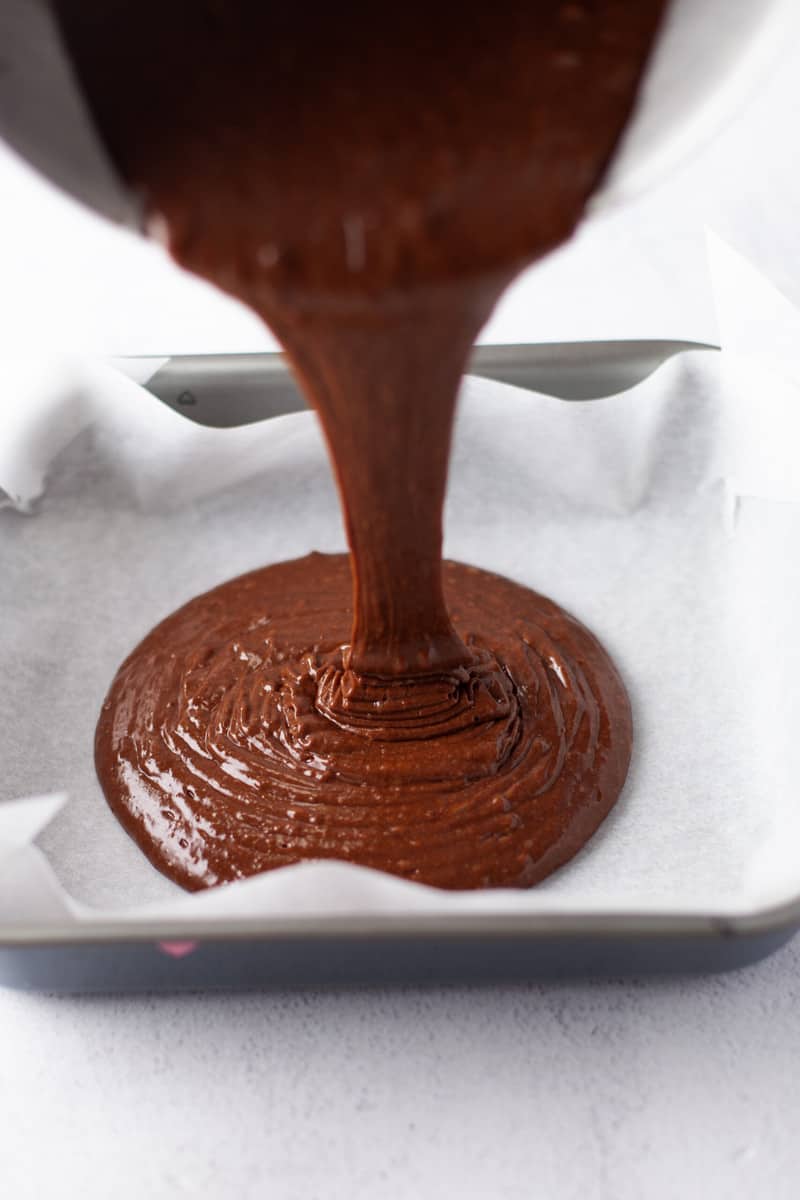 pouring batter into a lined baking pan.