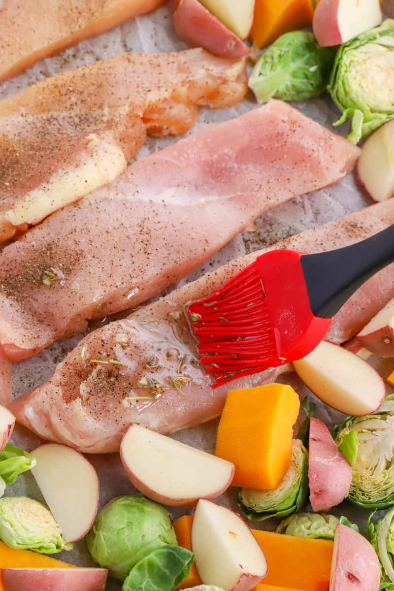 brushing the oil and spices on the chicken and veggies