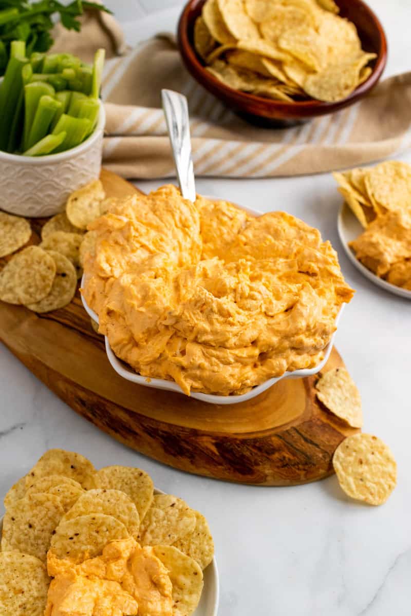 Buffalo Chicken Dip on wooden serving tray with tortilla chips and celery.