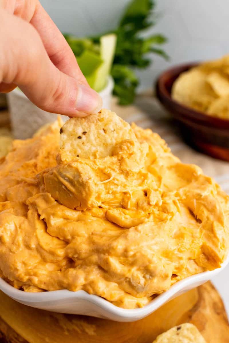 scooping buffalo chicken dip with a tortilla chip.