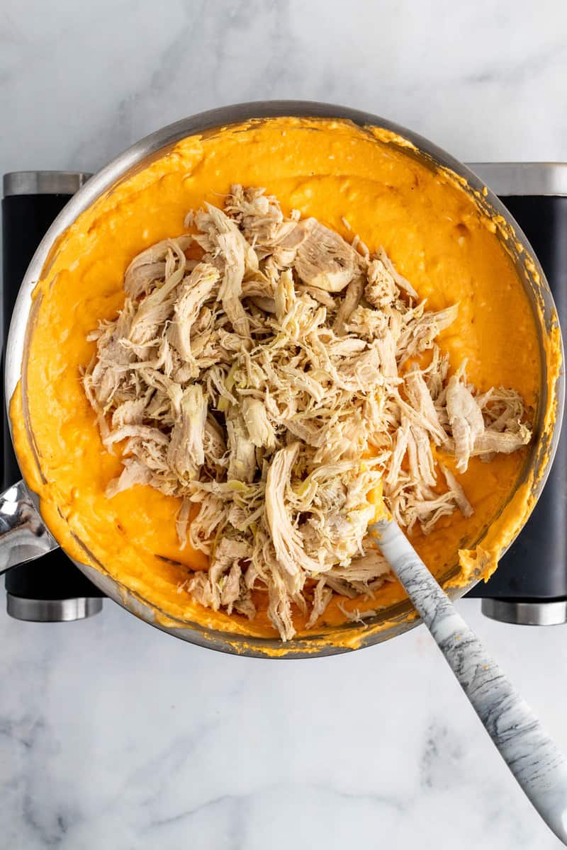 adding the shredded chicken to the dip.