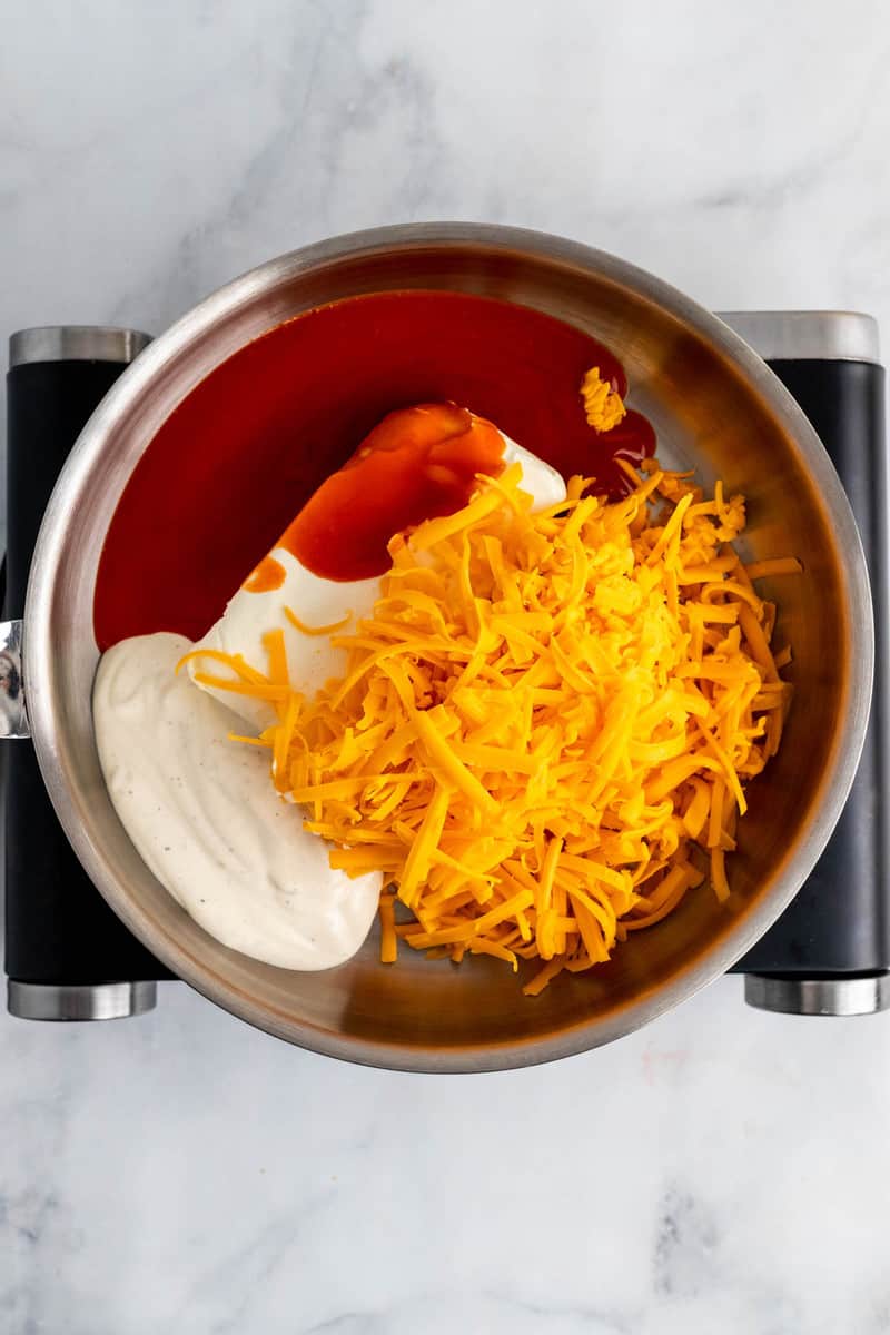 ingredients to make buffalo chicken dip in sauce pan.