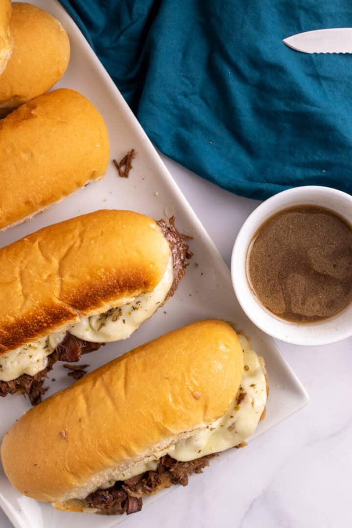 French Dip Sandwiches on white serving tray with au jus.