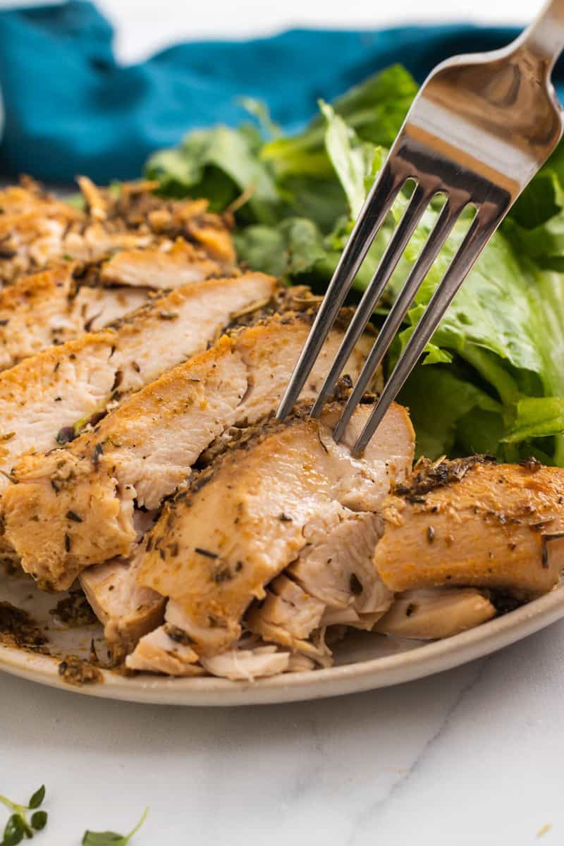 close up of sliced turkey breast being grabbed with a fork