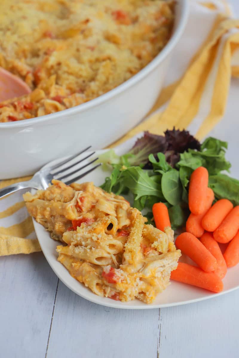 cheesy chicken casserole on a white plate with a salad