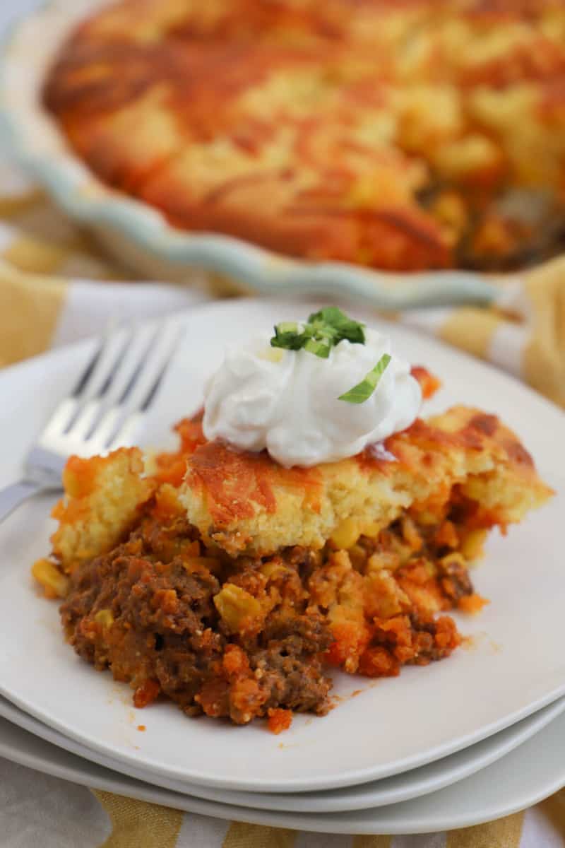 easy cornbread taco pie on white plate topped with sour cream