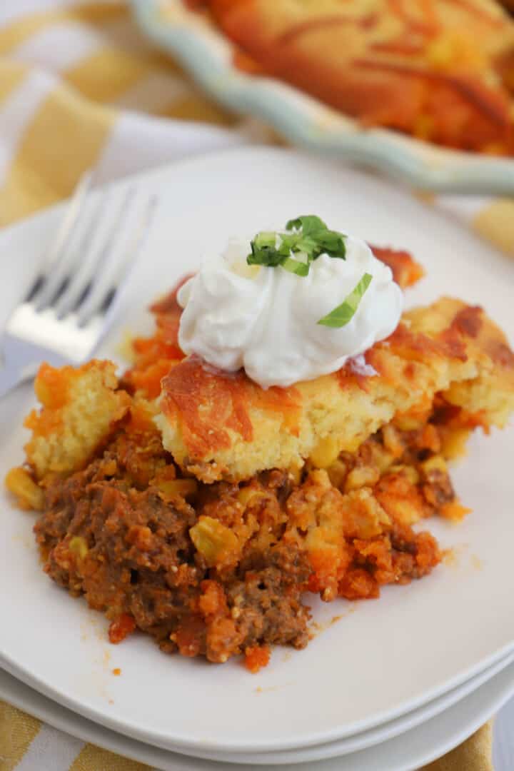 Easy Cornbread Taco Pie topped with sour cream on a white plate