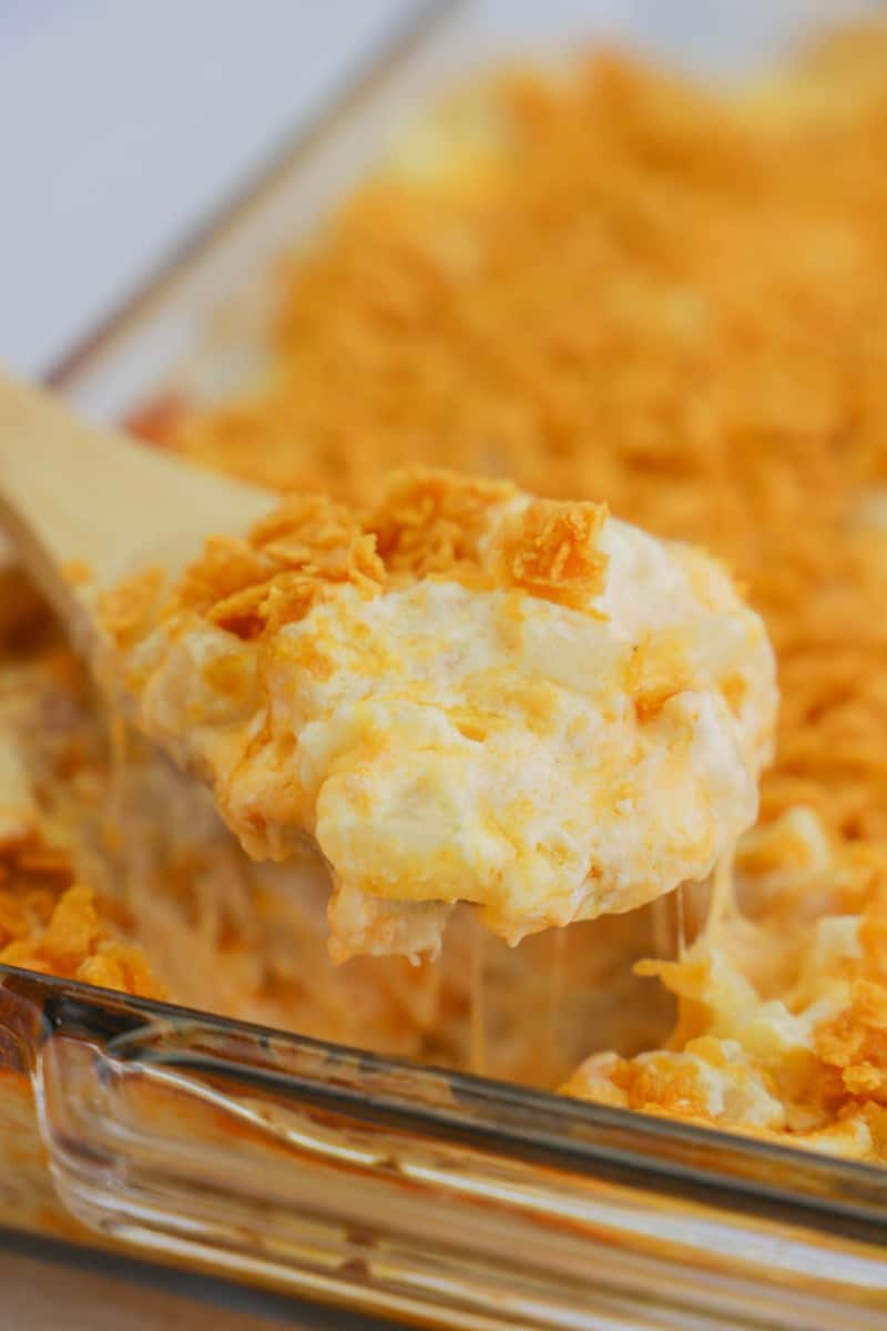 funeral potatoes being scooped out of dish on a wooden spoon