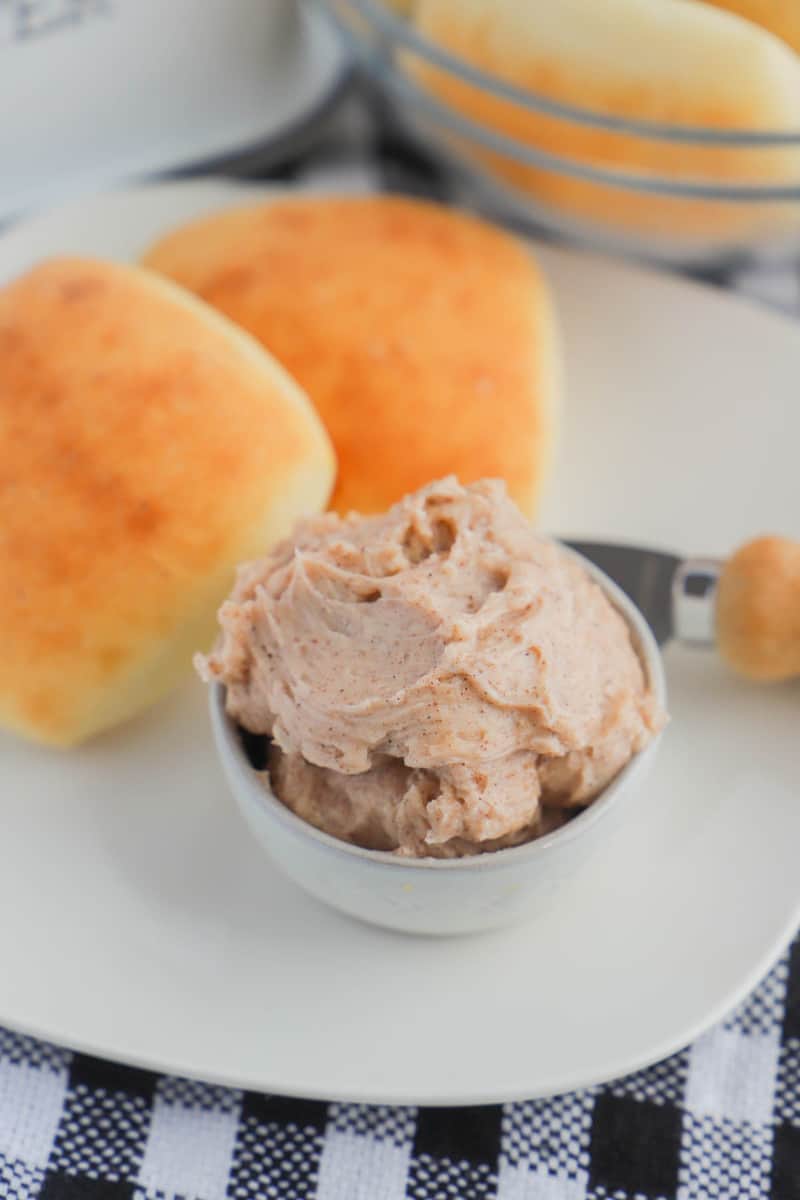 Honey Butter in a bowl next to some rolls on a white plate