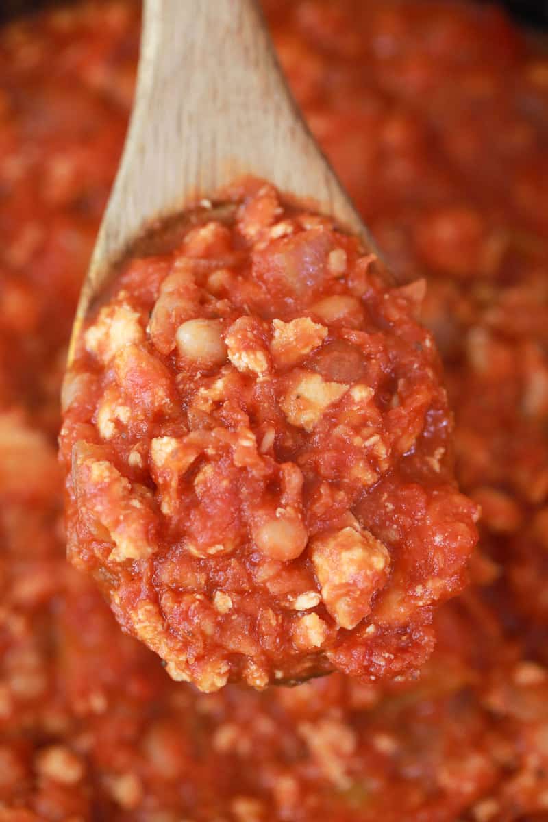 scooping chili out with a wooden spoon.