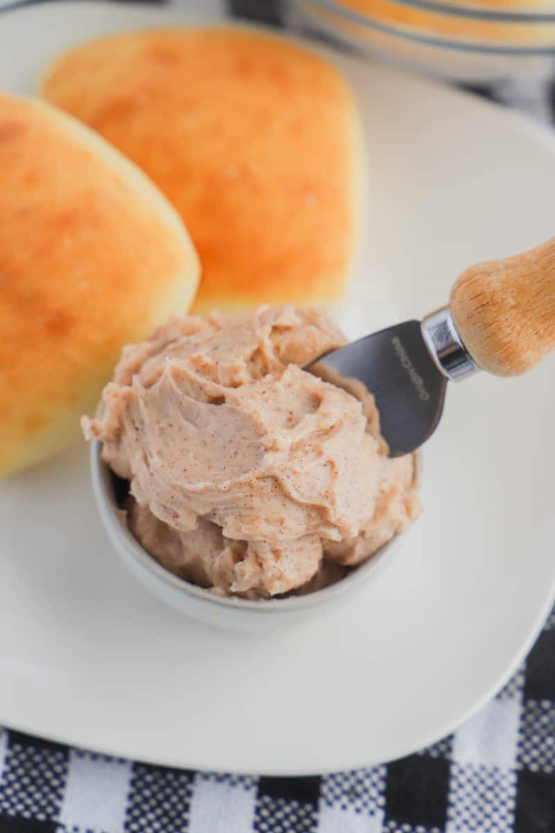 Honey Butter in a bowl next to some rolls on a white plate