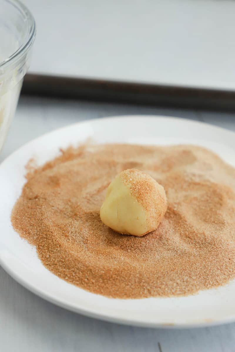 rolling cookie dough balls in cinnamon sugar mixture