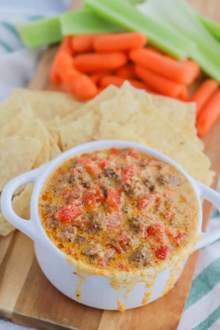 Rotel Dip in white serving bowl with tortilla chips carrots and celery